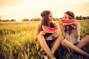Happy hipsters in field eating watermelow
